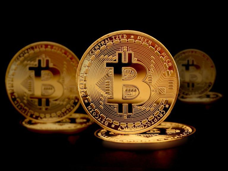 A detailed golden Bitcoin coin with circuit-like engravings, symbolizing cryptocurrency and blockchain technology, set against a dark background.